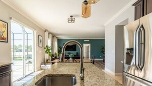 Una cocina con encimeras de granito, electrodomésticos de acero inoxidable y un amplio ventanal.