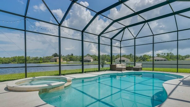 Una piscina exterior cubierta con vistas a un lago y casas al fondo.