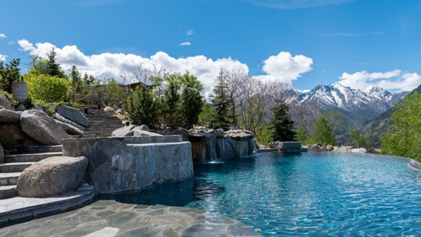 A pool with stone steps and a mountainous backdrop. - Red Roof Lodge - Leavenworth (Leavenworth)