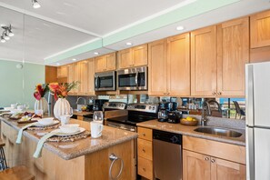 A modern kitchen with wooden cabinets, stainless steel appliances, and a granite countertop.