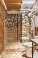 A bathroom with patterned tiles, a glass shower enclosure, and a toilet.