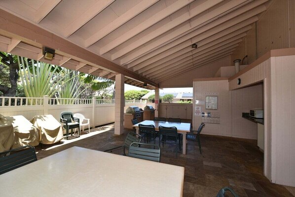 An outdoor patio with a covered dining area, a grill, and covered chairs.