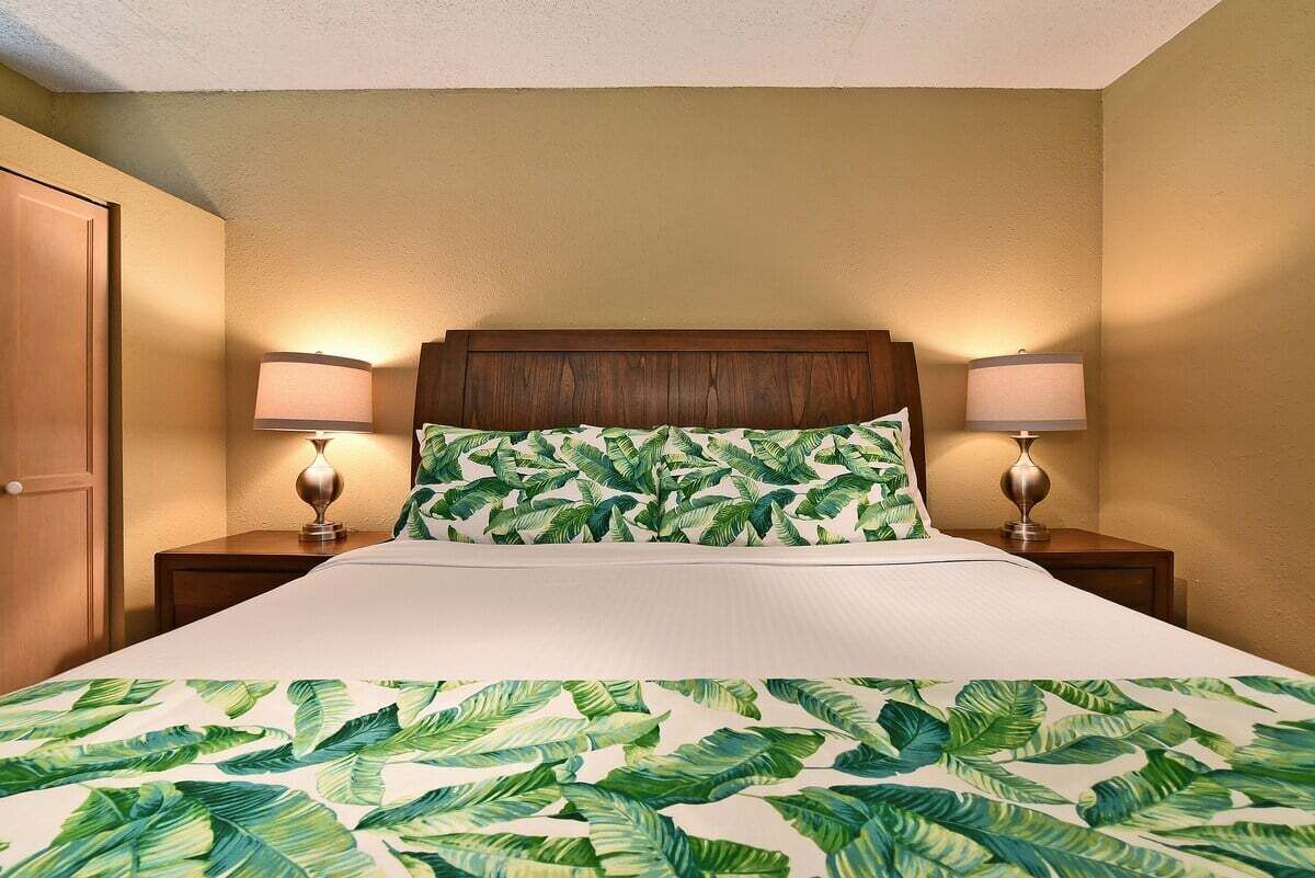 Een hotelkamer met een bed, twee bedlampjes en een houten hoofdeinde.