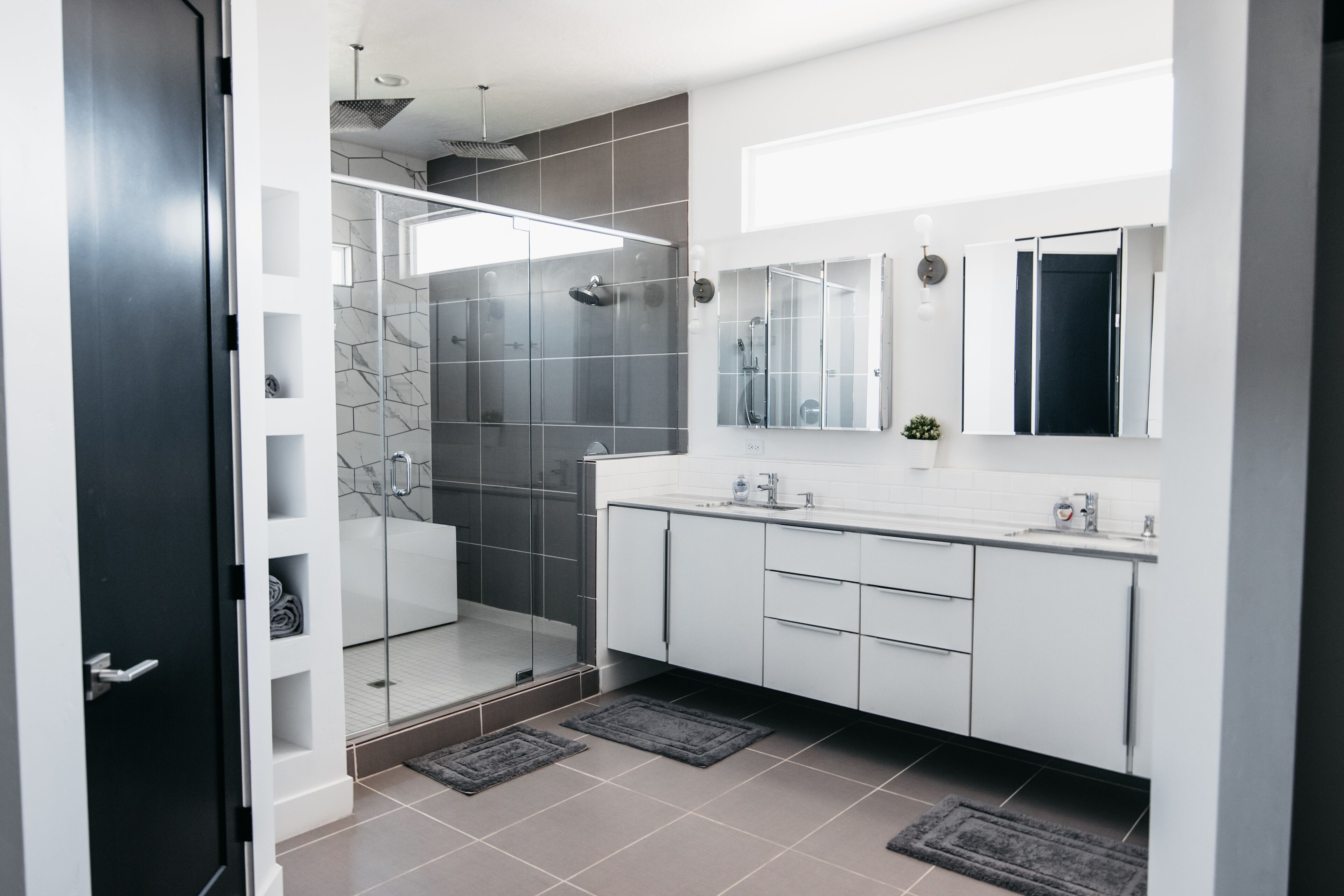 A modern bathroom with a glass-enclosed shower, white cabinets, and a large mirror.