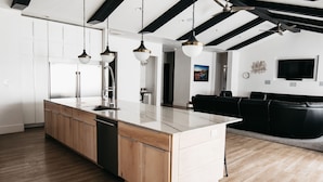 Una cocina moderna con armarios de madera, una isla grande e iluminación colgante.