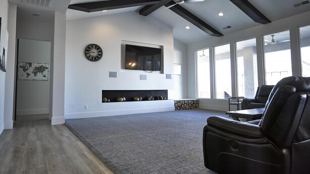 Un salón amplio con una televisión grande montada en la pared, una chimenea con adornos y un sillón de cuero.