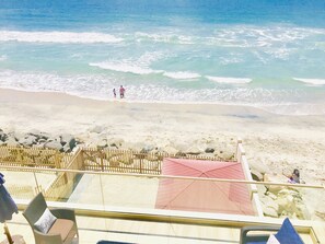Vista de la playa con una valla de madera y una construcción de techo rojo.