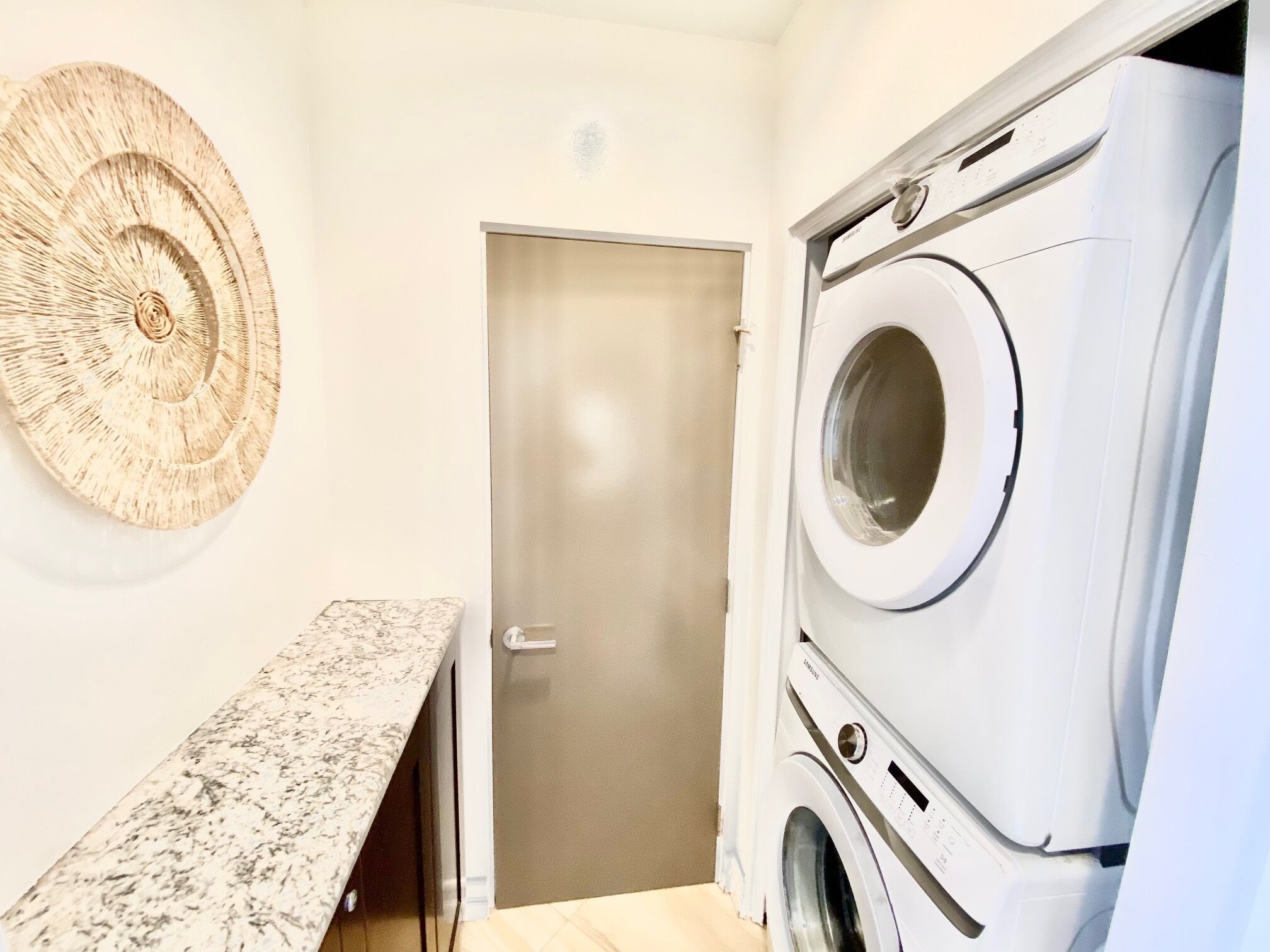 A laundry room with a washing machine, a door, and a bench.