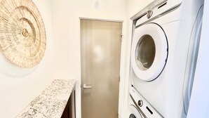 A laundry room with a washing machine, a door, and a bench. - 5 BR Large Beach House, Beachfront with Fire Ring,  Walk to Restaurants (Oceanside)