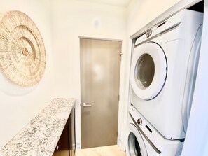 A laundry room with a washing machine, a door, and a bench. - 5 BR Large Beach House, Beachfront with Fire Ring,  Walk to Restaurants (Oceanside)
