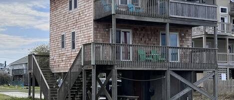 A multi-story wooden building with balconies and a staircase leading to the ground level.