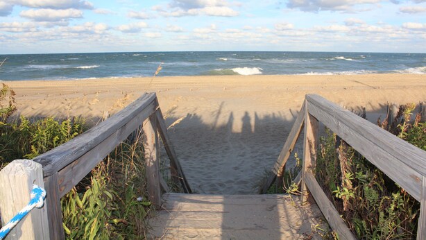 A wooden pathway leading to a sandy beach with the ocean in the background. - OBX, NC, Pristine Ocean Views without oceanfront price! (Kitty Hawk)