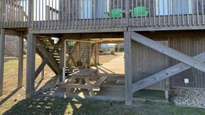A wooden deck with picnic tables and a covered area, connected to a building with windows and a balcony. - OBX, NC, Pristine Ocean Views without oceanfront price! (Kitty Hawk)