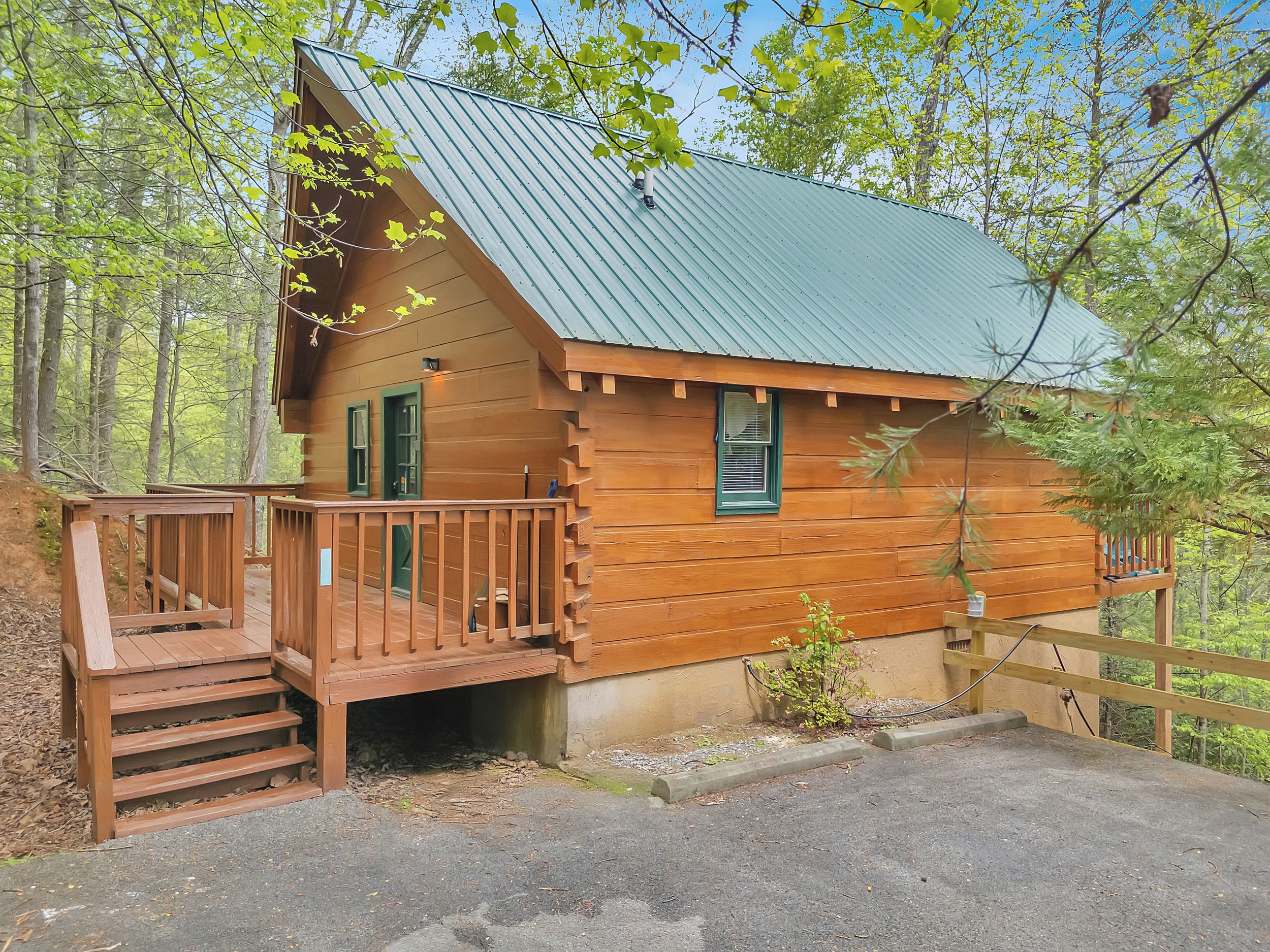 Une cabane en bois avec un toit en métal, une terrasse en bois et un petit porche.