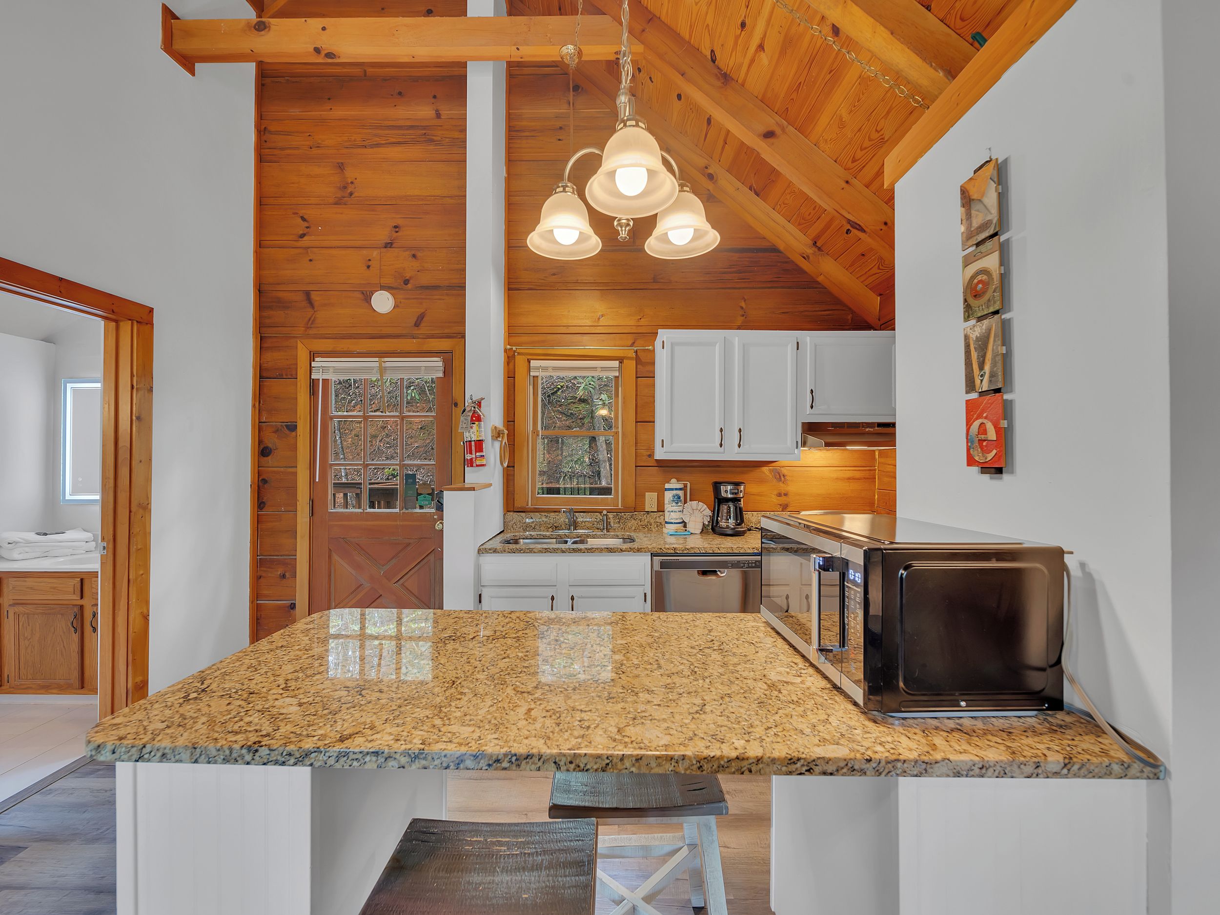 A kitchen with granite countertops, wooden cabinets, a built-in microwave, and a hanging light fixture.