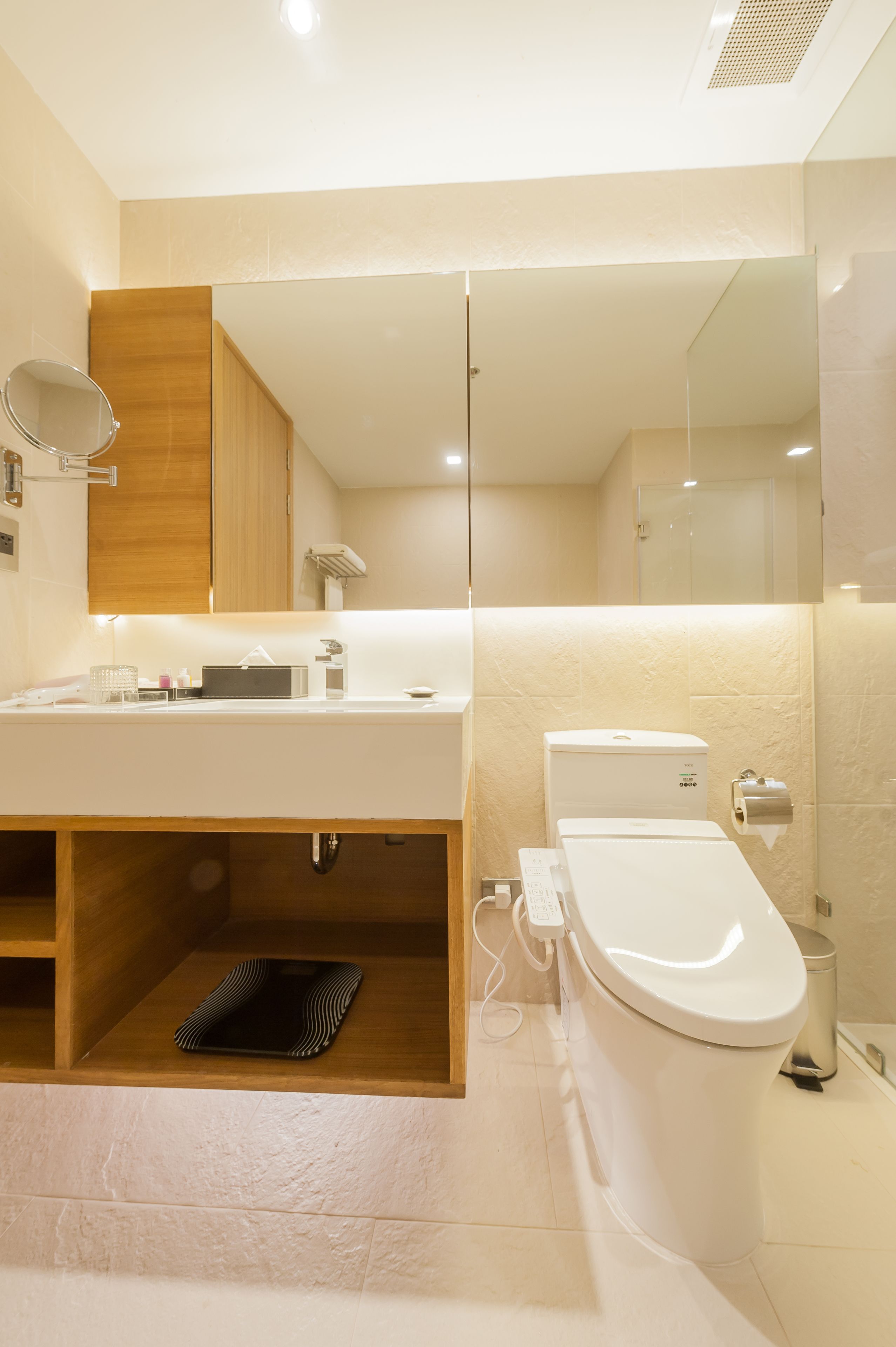 A modern bathroom with a wooden vanity, a toilet, and a bidet.