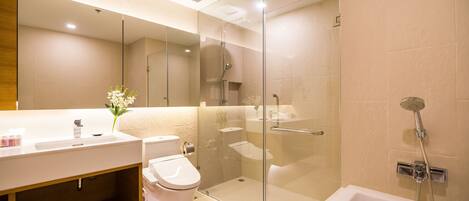 A modern bathroom with a glass-enclosed shower, a white sink, and a toilet.