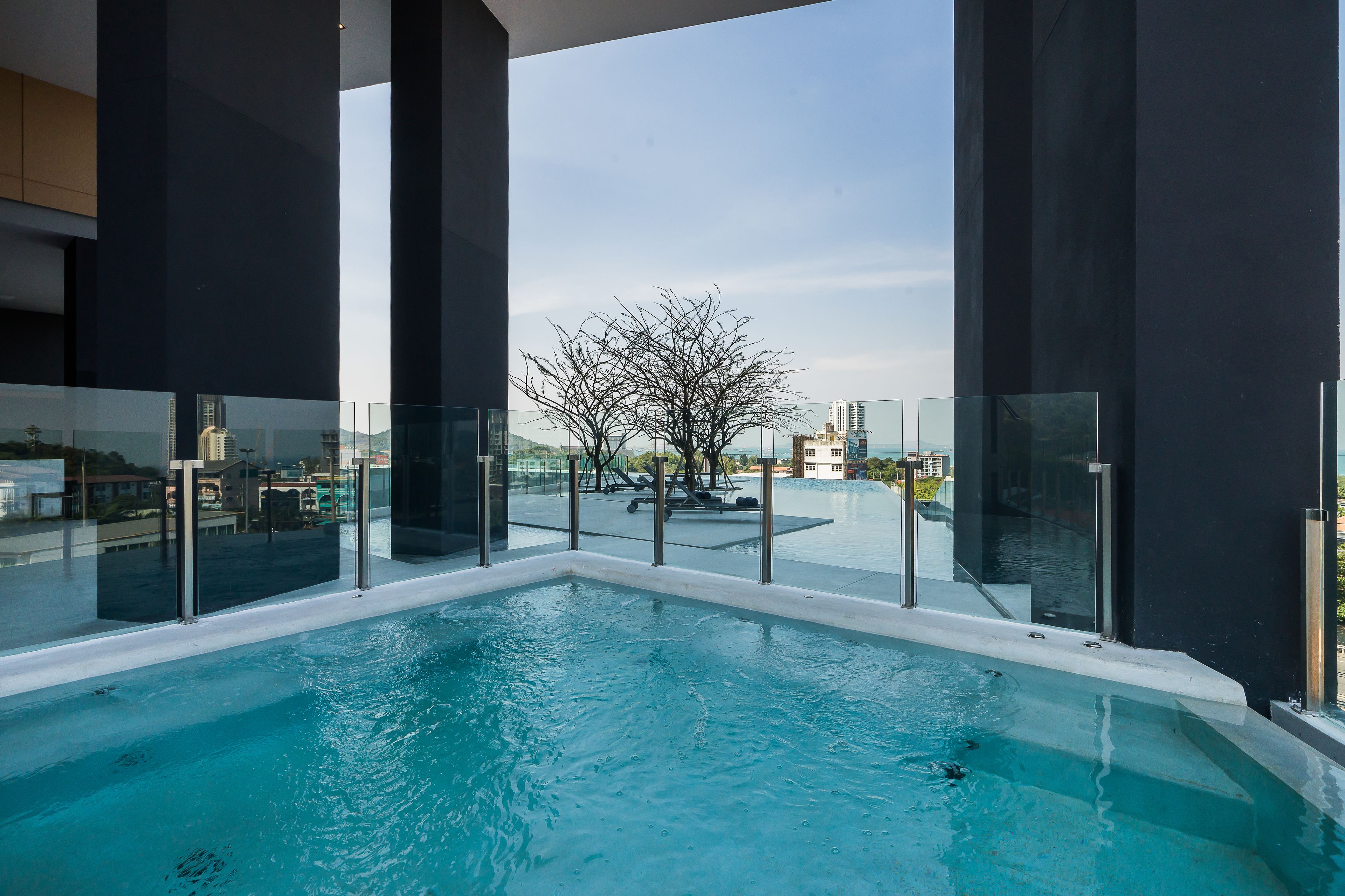 Une piscine intérieure moderne, dotée de rampes en verre et offrant une vue sur le paysage urbain.