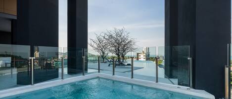 Une piscine intérieure moderne, dotée de rampes en verre et offrant une vue sur le paysage urbain.