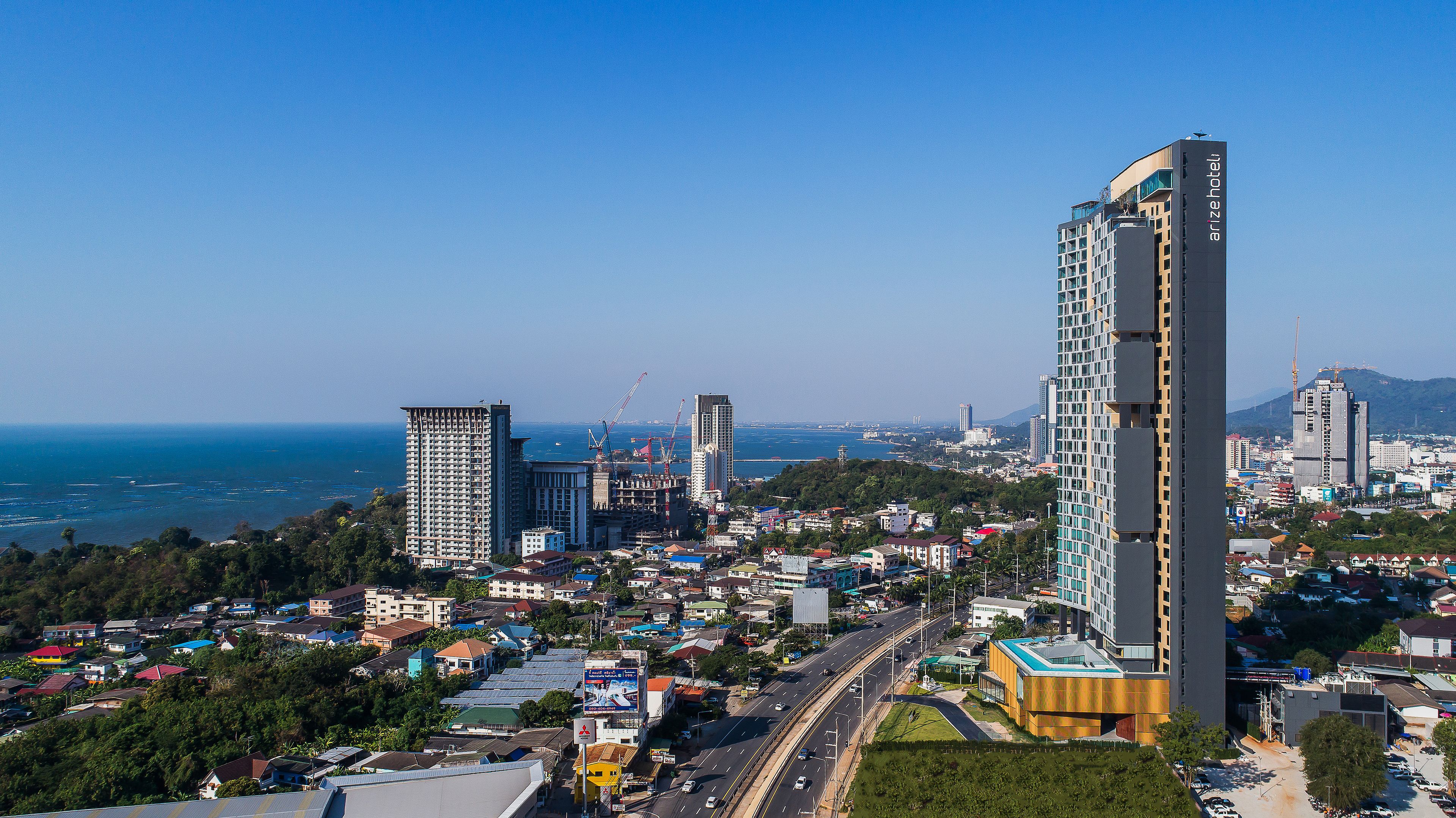 Un hôtel de grande hauteur, avec de nombreux étages, une entrée imposante et une vue sur le paysage urbain et la côte environnants.