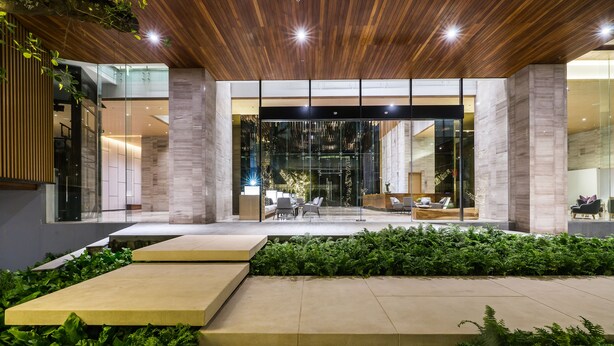 Un bâtiment moderne doté d’un plafond en bois, de grandes portes vitrées et d’un espace détente avec des meubles d’extérieur.