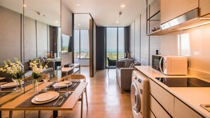 Cuisine moderne équipée d’un four à micro-ondes, d’un four et d’un lave-linge. Elle comprend un coin repas avec une table pour deux personnes et un canapé.