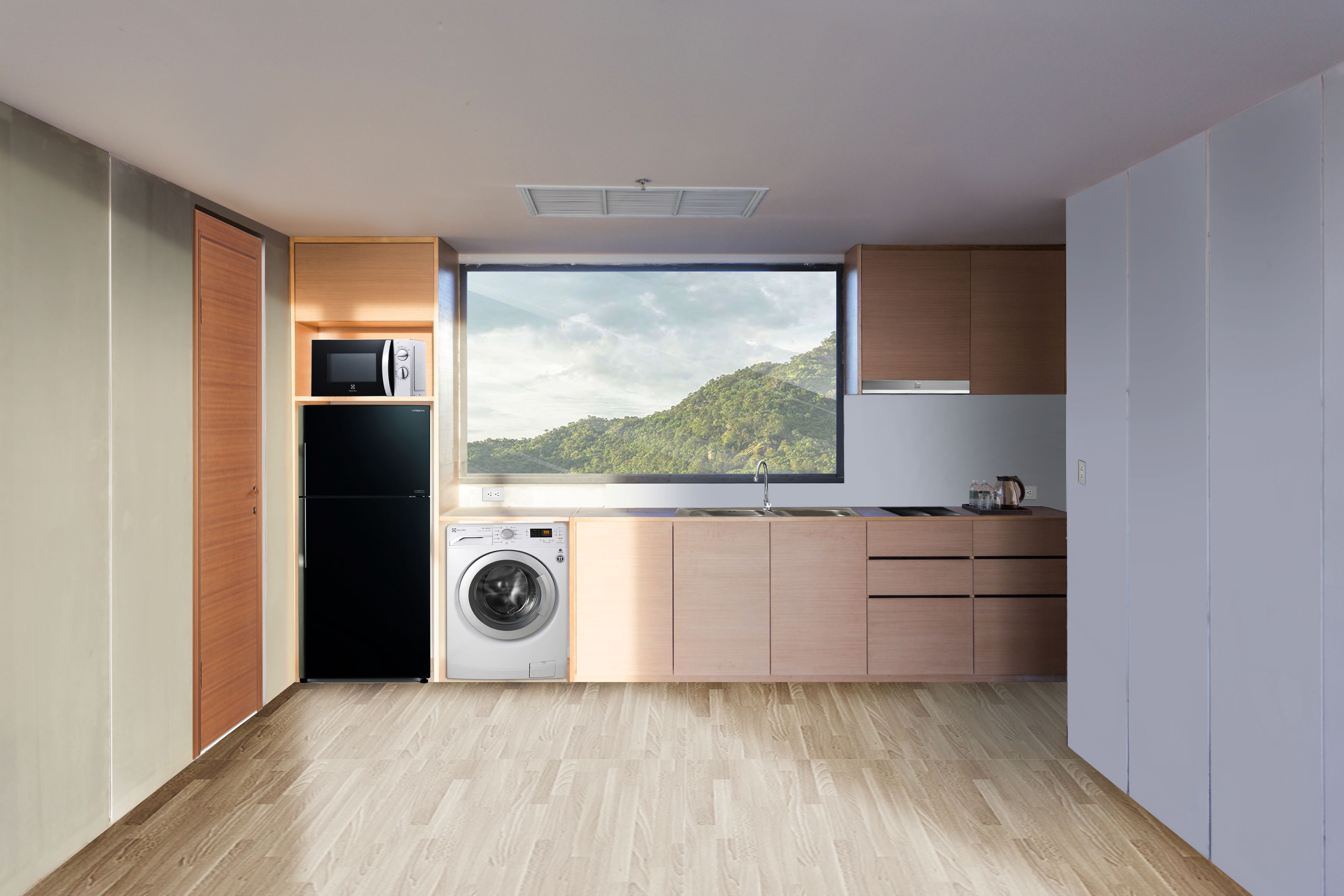 A compact kitchen with a washing machine, a microwave, and a large window offering a view of a green landscape.