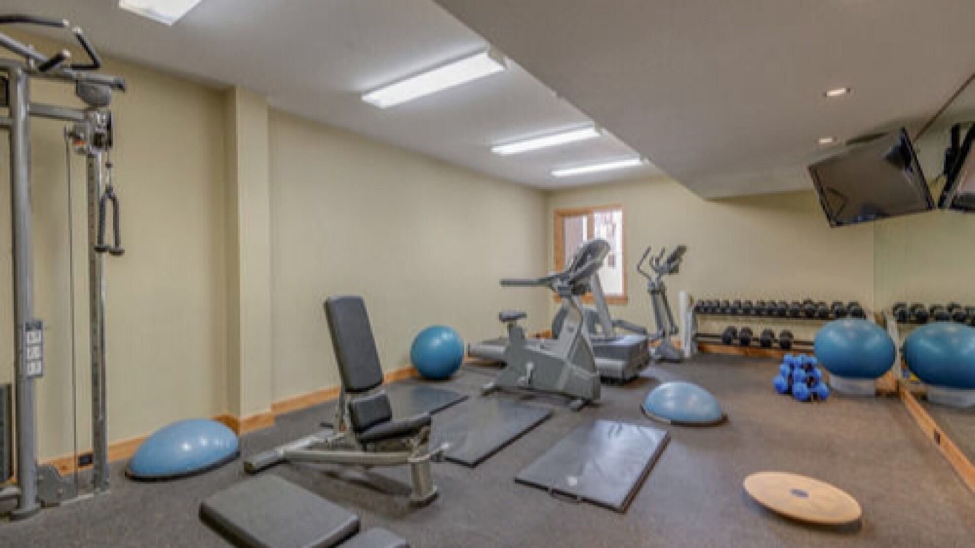 A gym with exercise equipment, treadmills, and free weights.
