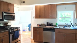A modern kitchen with wooden cabinets, stainless steel appliances, and a large window providing natural light.