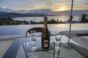 A table with a bottle of Chandon champagne and two glasses, overlooking a coastal view with boats and mountains. - 3 Bedroom Sea View Sunset Apartment SDV120-By Samui Dream Villas (Koh Samui)