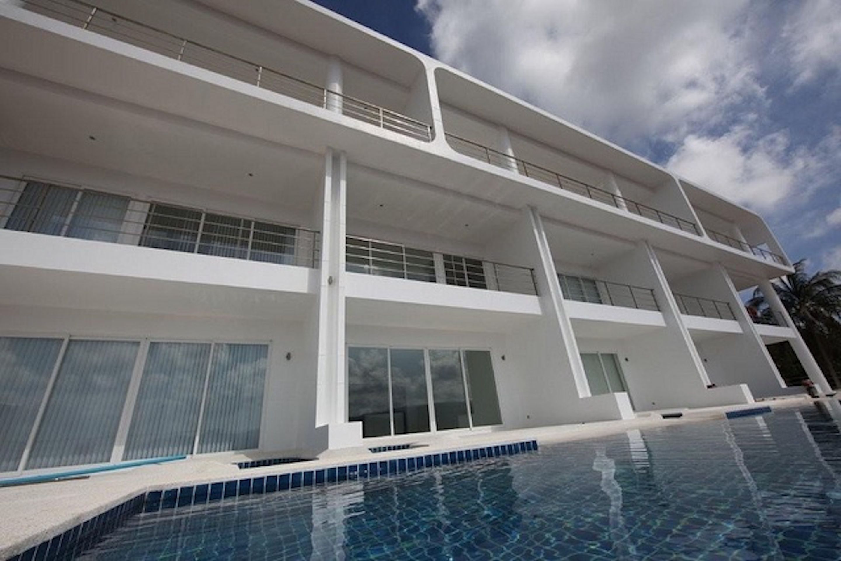 A modern multi-story building with a pool in the foreground.