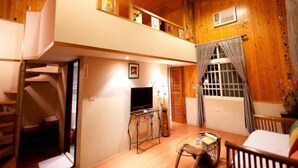 A cozy, wooden-floored living area with a TV, a small table, and a chair. A staircase leads to an upper level with a balcony. - Country View B&B (Ji'an)