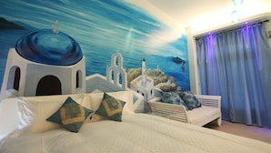 A hotel room with a mural of a coastal scene, a bed with white bedding, and a view of the sea through a window with blue curtains. - Country View B&B (Ji'an)