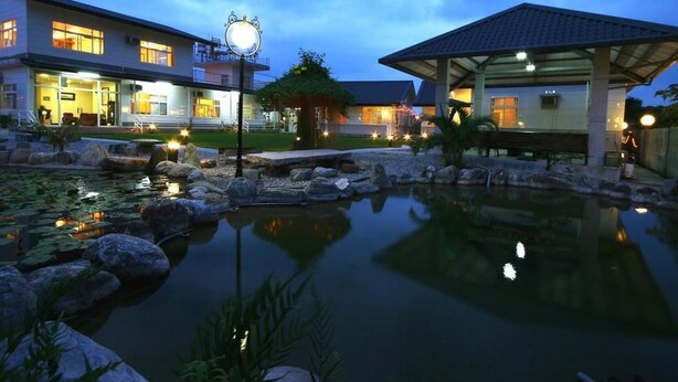 A hotel with a large outdoor pool, a covered pavilion, and a well-lit building with multiple windows. - Country View B&B (Ji'an)