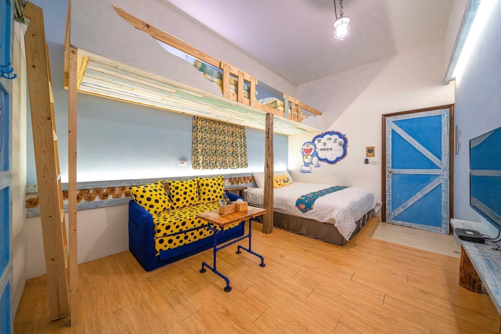 Habitación compacta con una litera, un sofá estampado con lunares, una mesita pequeña y una cama con cabecera a rayas azules y blancas.