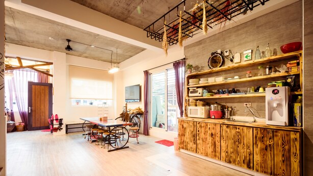 A spacious kitchen with wooden cabinetry, a dining area with a table and chairs, and a bicycle in the corner. - Anping 156 B&B (Tainan)