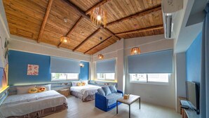 A room with a wooden ceiling, two beds, a blue sofa, a small table, and a TV. - Anping 156 B&B (Tainan)