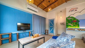 A living room with a blue wall, a flat-screen TV, a wooden table, and a patterned sofa. - Anping 156 B&B (Tainan)