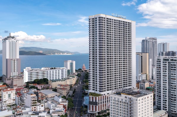 A high-rise hotel with a grid-like facade, situated in a coastal cityscape with a view of the sea and mountains in the background. - Vinpearl Empire Nha Trang, Affiliated by Meliá (Nha Trang)