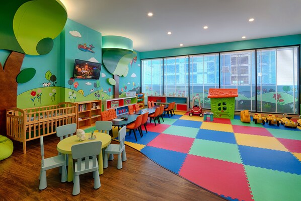 A children's playroom with a colorful floor, wooden furniture, and a large window. - Vinpearl Empire Nha Trang, Affiliated by Meliá (Nha Trang)