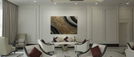 Un salón amplio con una lámpara araña moderna, un cuadro abstracto grande y un conjunto de sofás.