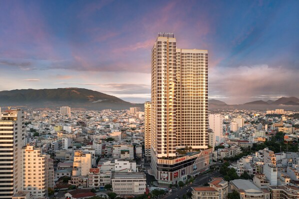 A high-rise hotel with a modern design, surrounded by a densely packed urban area with various buildings.