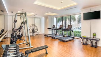A modern gym with treadmills, weight machines, and benches.