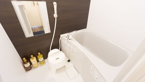 Un baño con bañera, inodoro y espejo. Hay artículos de tocador en la encimera.