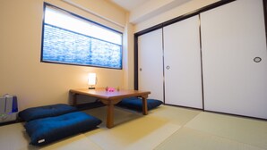 Una habitación japonesa tradicional con suelo de tatami, una mesa de madera baja y cojines azules.