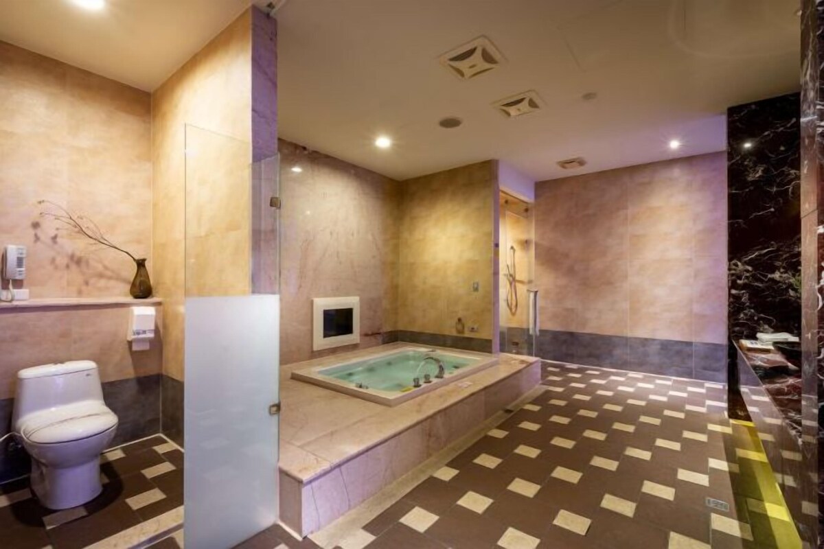 A modern bathroom with a large bathtub, a toilet, and a shower area.
