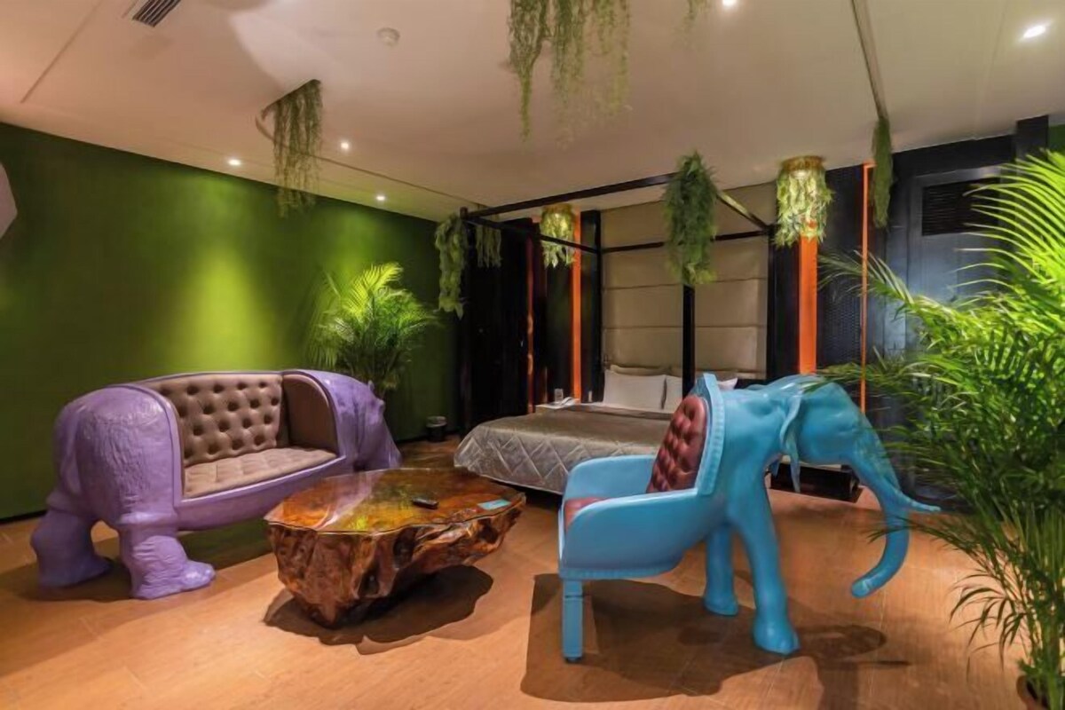 Una habitación con una cama, dos sofás con forma de elefante, una mesa de centro y plantas colgantes.