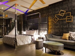 A modern bedroom with a four-poster bed, a glass-enclosed shower, a dark wood accent wall, and a geometric gold decoration. - Vogue Boutique Motel (Taoyuan City)