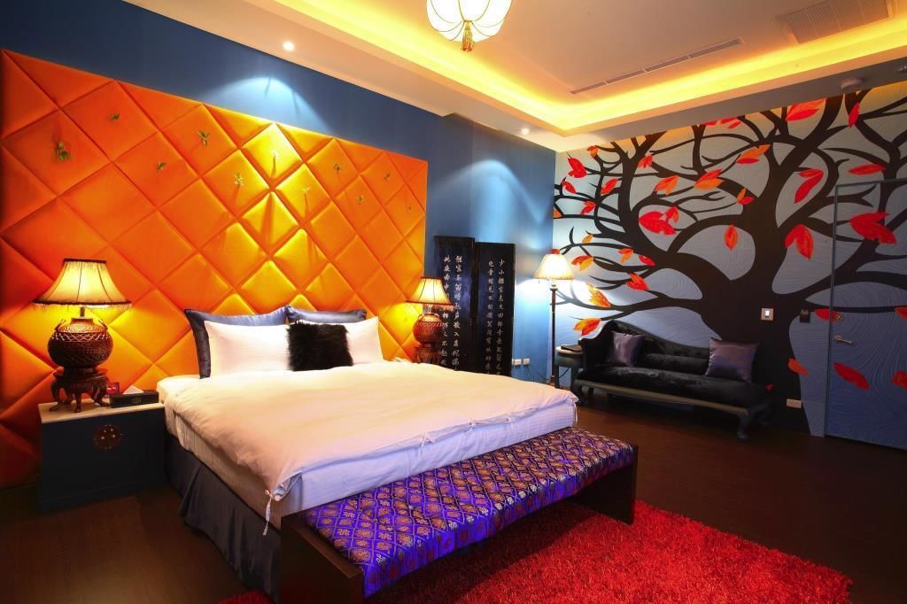 A modern bedroom with a large bed, a red carpet, and a wall mural of a tree.