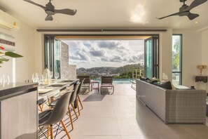 A modern dining area with a view of a cityscape. - Baan Saint Tropez Villas Kata Beach (Karon)